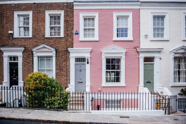 In front of a row of differently coloured brick houses in the concept of 'Best Affordable Housing Options When Moving to Harrow'.