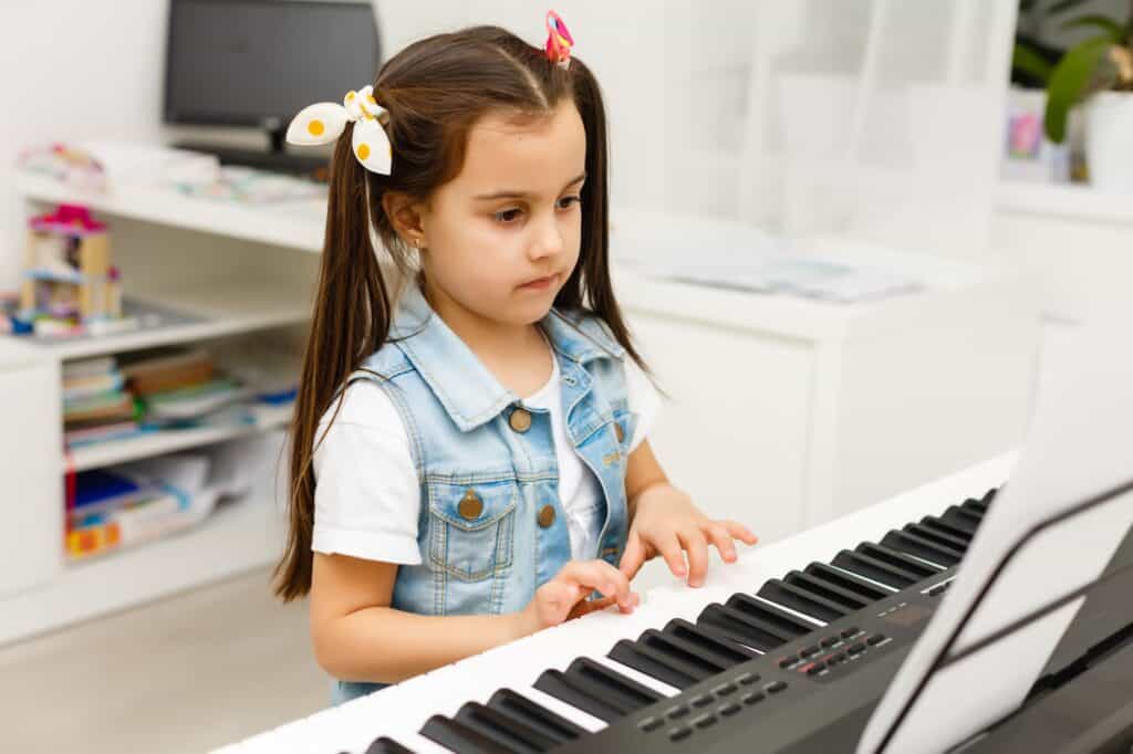 A young female student playing the piano during the music class